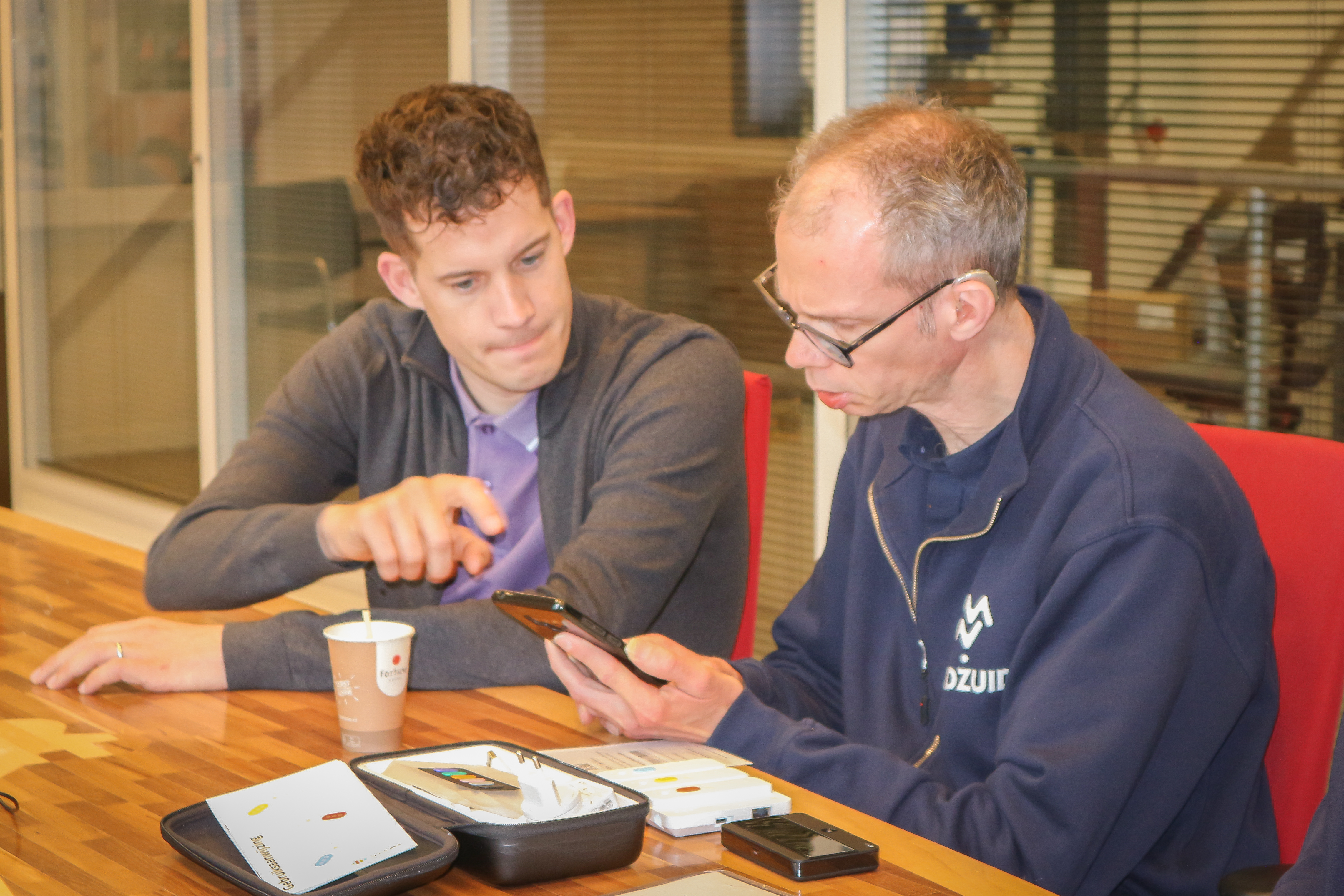 Collega Patrick kijkt met een collega van MIdZuid naar het programma Speaksee op de mobiele telefoon